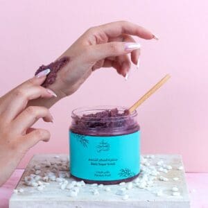 A luxurious Passion Fruit Body Sugar Scrub, open and being applied to the back of a hand